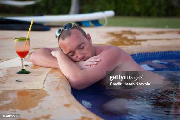 sunburned man asleep with drink in hot tub. - sunburn stock-fotos und bilder