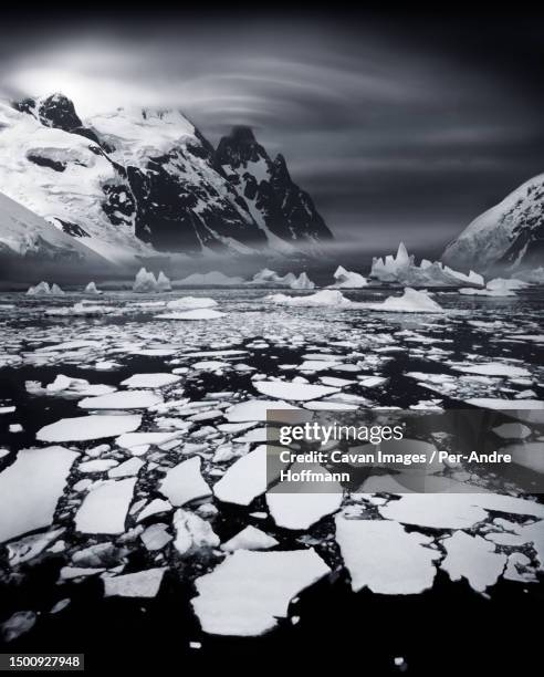 ice shoals near the antarctic circle with lenticularis cloud over mountain peak. usually this area is frozen - naturwunder photos et images de collection