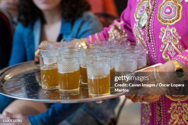 moroccan woman carrying a tray with tea for the guests of a party - agadir stock pictures, royalty-free photos & images