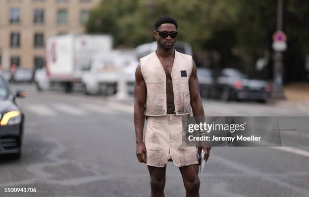 Sadiq Desh is seen wearing brown shades, matching two piece with a beige utility vest and mini shorts, white socks and black leather boots outside...