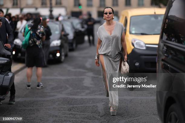 Fashion Week guest is seen wearing a silver long dress, shades and gold drops earring, silver bracelet and platform silver heels outside Givenchy...