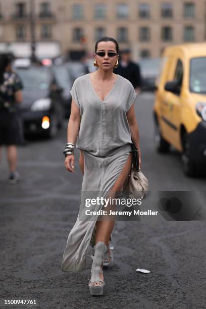 Fashion Week guest is seen wearing a silver long dress, shades and gold drops earring, silver bracelet and platform silver heels outside Givenchy...