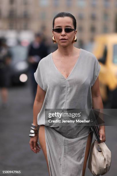 Fashion Week guest is seen wearing a silver long dress, shades and gold drops earring, silver bracelet and platform silver heels outside Givenchy...