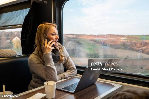 une femme est assise dans le train et parle au téléphone - woman blond looking left window photos et images de collection
