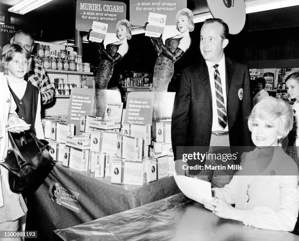 American comedienne, actress, singer and businesswoman Edie Adams signs autographs for her fans as store manager of Schuman Drug Store, Marshal...