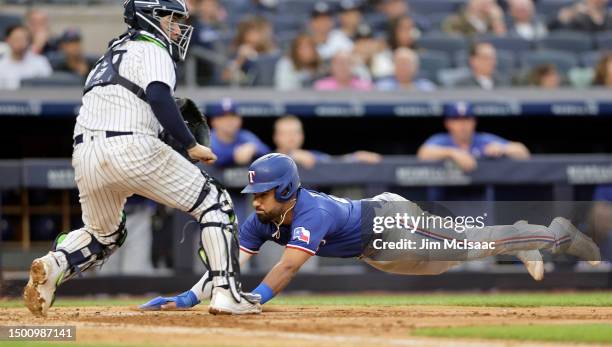 Ezequiel Duran of the Texas Rangers dives home for a run during the fourth inning against Jose Trevino of the New York Yankees at Yankee Stadium on...