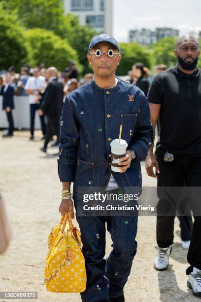 Pharrell Williams wears cap, denim jacket, jeans, yellow bag outside Dior during the Menswear Spring/Summer 2024 as part of Paris Fashion Week on...