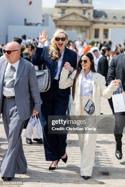 Gwendoline Christie wears navy jacket, pants, silver bag & Demi Moore wears creme white suit outside Dior during the Menswear Spring/Summer 2024 as...