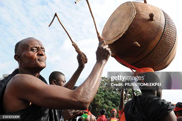 Man plays the drum as he gathers with other Ghanaian mourners to watch the casket carrying the remains of late Ghanaian President John Atta Mills...