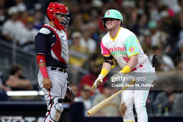 Jake Cronenworth of the San Diego Padres reacts after being hit by a pitch as Keibert Ruiz of the Washington Nationals looks on during the seventh...