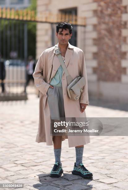 Rahi Chadda is seen wearing a beige light trenchcoat, blue flanell shirt, grey striped shorts, beige crossbody Christian Dior saddle bag, blue knit...