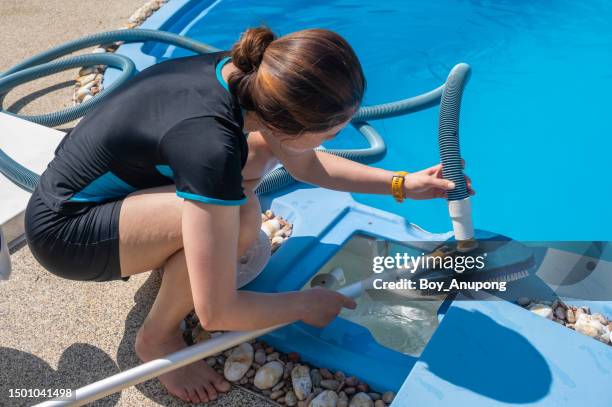 young housekeeping while setting a pool vacuum brush into pool plumbing before cleaning pool. - swimming pool cleaning stock pictures, royalty-free photos & images