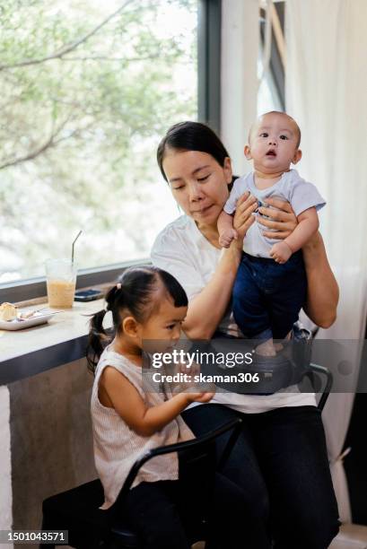 positive emotion asian family with two children enjoy and leisure at cafe weekend activity domestic life - mom taking photos of baby eating imagens e fotografias de stock