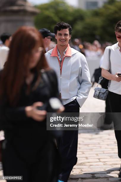 Adam DiMarco is seen wearing a striped light blue jacket, neon orange shirt and navy blue wide leg pants outside Dior Homme during the Menswear...