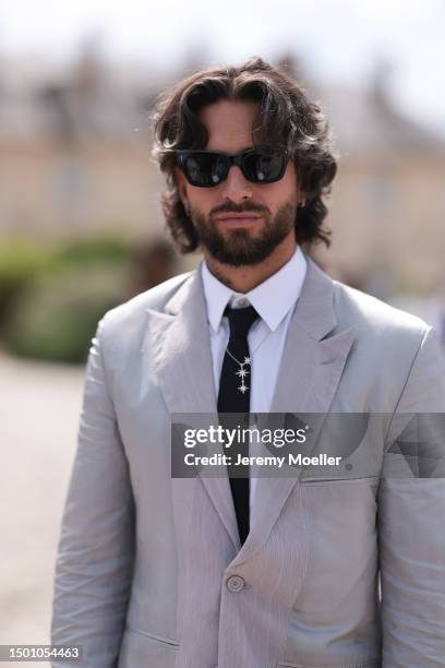 Maluma is seen wearing a grey suit with blazer and grey suit pants, black shades, black tie, silver chain and olive leather Dior saddle bagoutside...