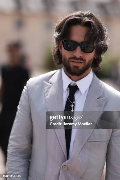 Maluma is seen wearing a grey suit with blazer and grey suit pants, black shades, black tie, silver chain and olive leather Dior saddle bagoutside...