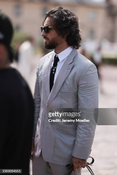 Maluma is seen wearing a grey suit with blazer and grey suit pants, black shades, black tie, silver chain and olive leather Dior saddle bagoutside...