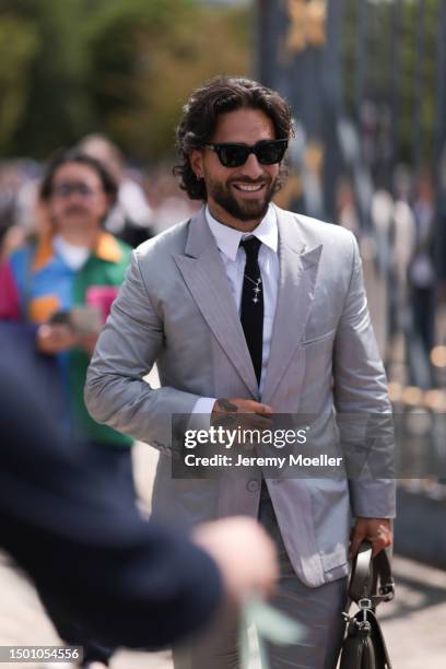 Maluma is seen wearing a grey suit with blazer and grey suit pants, black shades, black tie, silver chain and olive leather Dior saddle bagoutside...