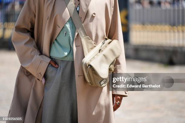 Rahi Chadda wears a pale green with pale gray borders cargo shirt from Dior, a beige long coat, a beige fabric crossbody Saddle clutch from Dior,...