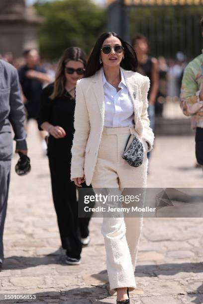 Demi Moore is seen wearing a tweed light creme blazer with shoulder pads and matching creme wide leg tweed pants, white flanell, black heels and...