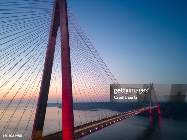 sunset in istanbul: cargo ship passing under yavuz sultan selim bridge at sunrise - steel stock pictures, royalty-free photos & images