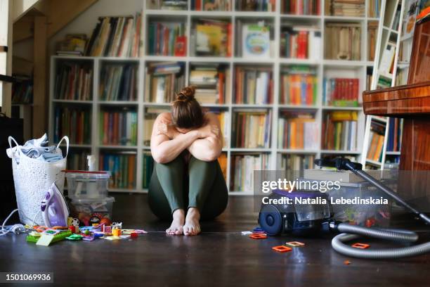 weighed down: depressed overweight woman in closed-off child-like position beside household cleaning tools and laundry basket - obsession photos et images de collection