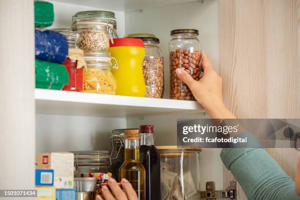 female hand picking ingredient for cooking from kitchen cabinet - voorraadkast stockfoto's en -beelden