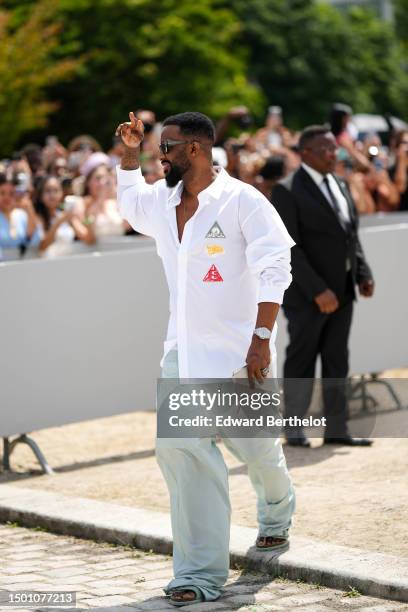 Guest wears black squared sunglasses from Dior, a silver chain necklace, a white shirt red / yellow / gray embroidered yoke from Dior, a silver and...