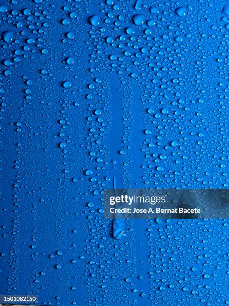 a drop of water slides down a blue wet surface. - wateroppervlak stockfoto's en -beelden