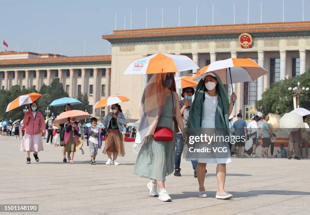 Tourists use umbrellas and protective clothing to shade from the sun at Tiananmen Square as the city temperature reaches 40 degree celsius on June...