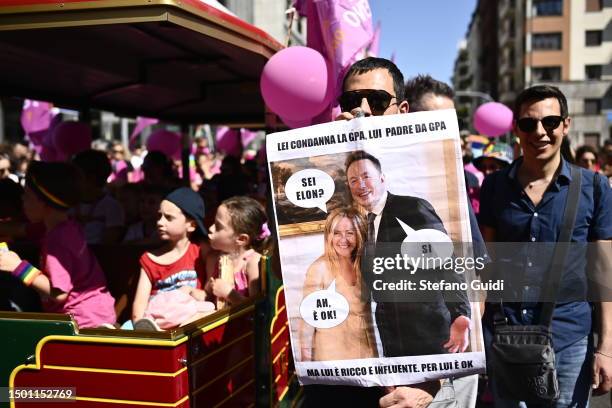 People hold up a sign with Elon Musk and Italian Prime Minister Giorgia Meloni on it as they attend Milano Pride 2023 on June 24, 2023 in Milan,...