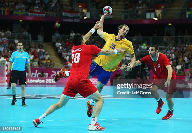 Kim Ekdahl du Rietz of Sweden shoots between Timuzsin Schuch and Ferenc Ilyes of Hungary during the Men's Handball semifinal game between Hungary and...