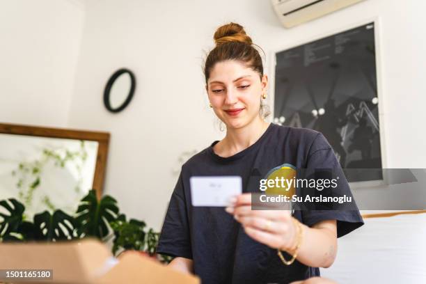 mujer joven recibiendo un regalo y leyendo la nota dentro - tarjeta de regalo fotografías e imágenes de stock