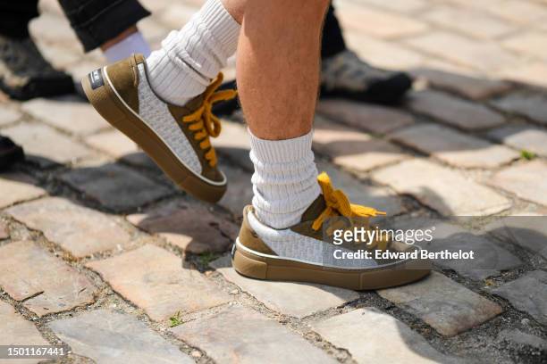 Guest wears white socks, white and gray Dior Oblique Jacquard print pattern fabric / brown suede / yellow laces sneakers from Dior , outside Dior,...