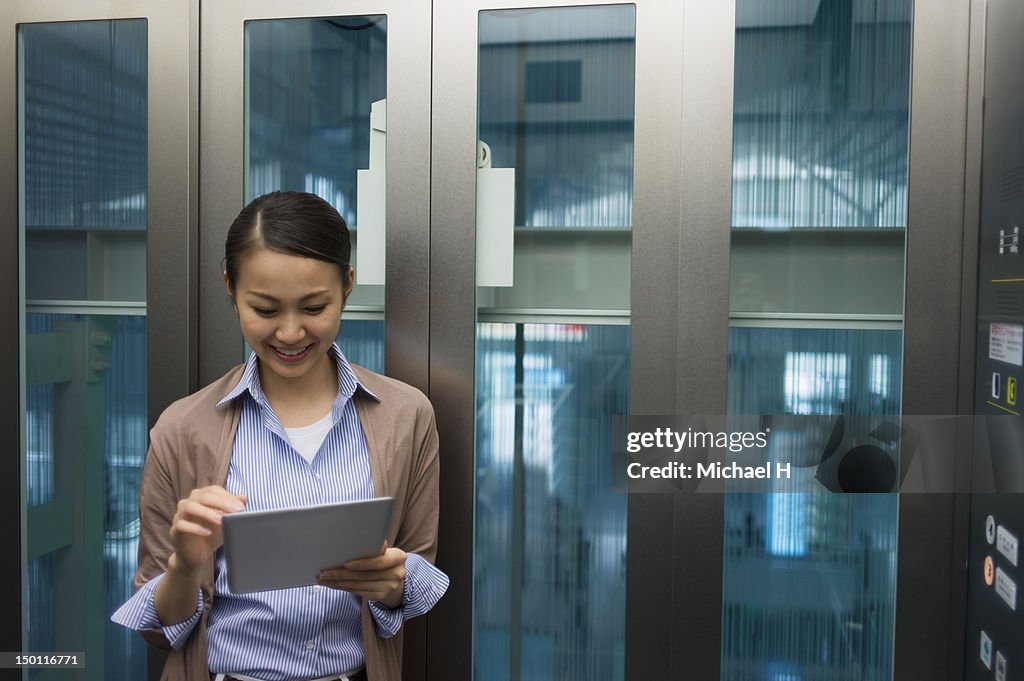 Office lady using a Tablet PC in a elevator