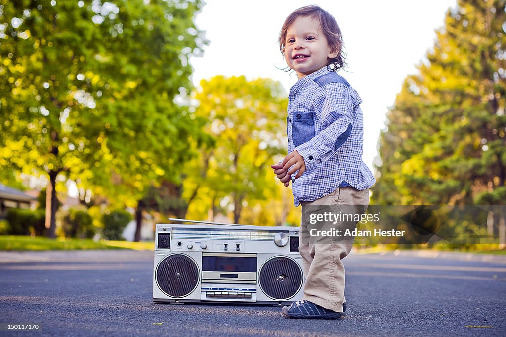 A young boy standing with a stereo outside.
