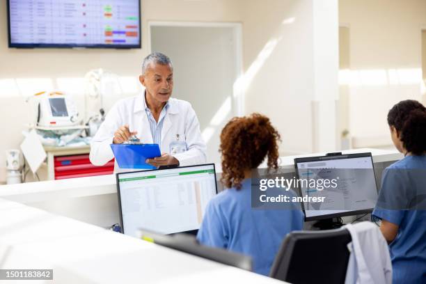 médico conversando com recepcionistas do hospital - posto das enfermeiras - fotografias e filmes do acervo