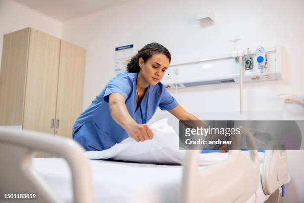 krankenschwester, die ein bett in einem krankenhauszimmer macht - hospital stock-fotos und bilder