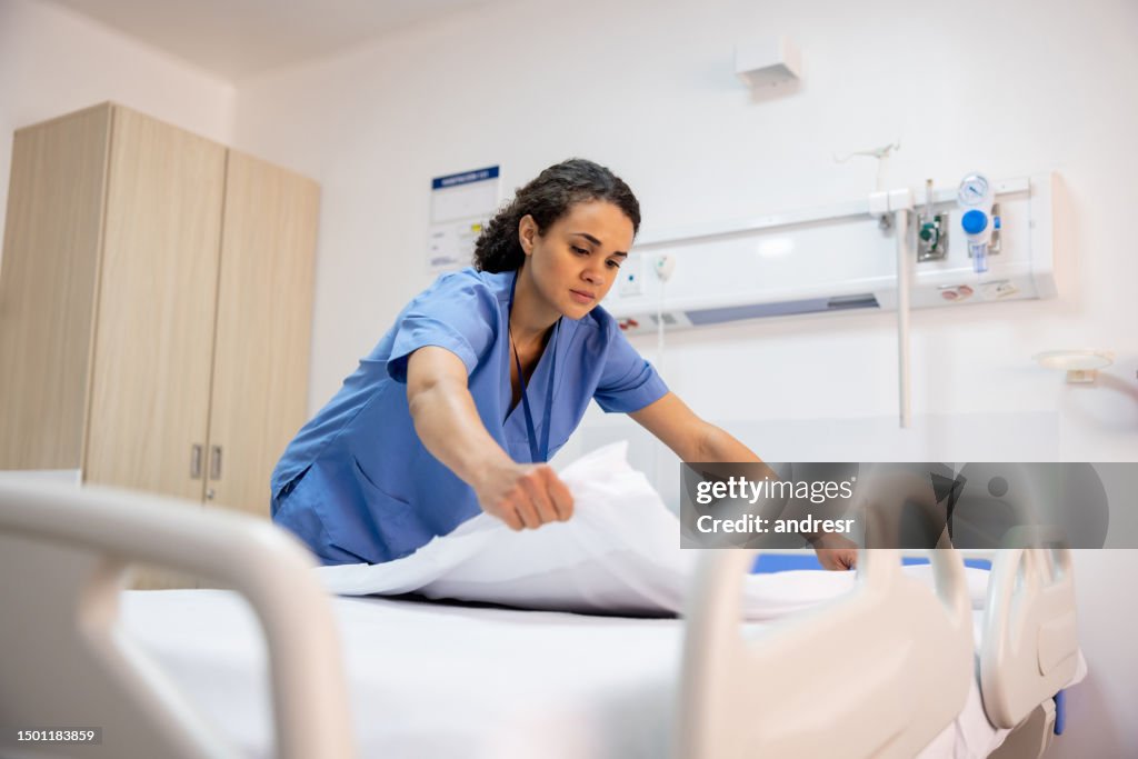 Enfermeira fazendo uma cama em um quarto de hospital