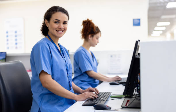 A woman smiling at the camera and sitting in front of a computer in a hospital setting