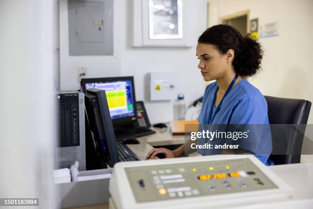radiologist working in the control room while taking an x-ray image - medical technologist stock pictures, royalty-free photos & images