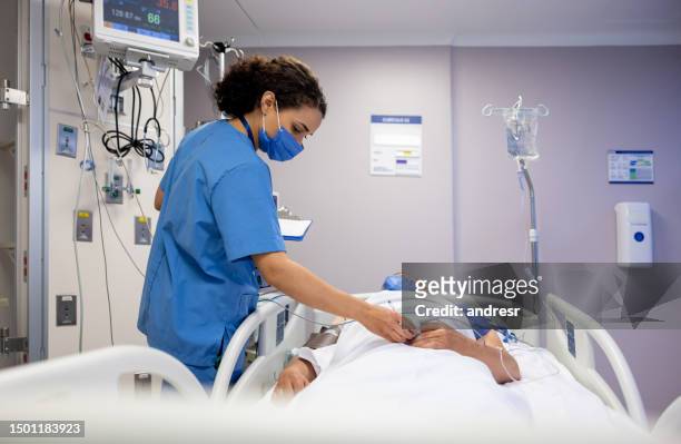 nurse checking on a patient at the hospital - icu stockfoto's en -beelden