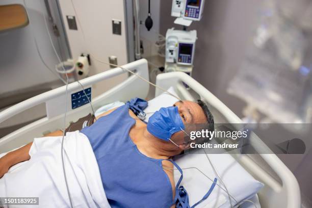 hospitalized man wearing a face mask while lying on a bed at the icu - infectious disease 個照片及圖片檔