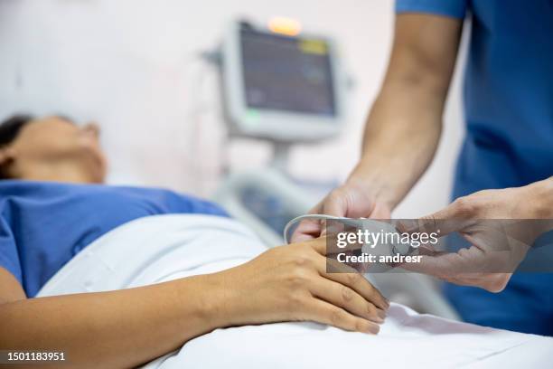 nurse placing a pulse oximeter on a patient at the hospital - pulse oximeter stockfoto's en -beelden