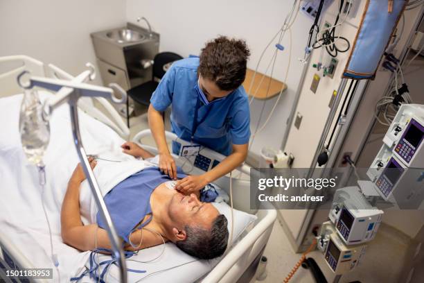 une infirmière place des électrodes sur un patient à l’hôpital - rythme cardiaque photos et images de collection