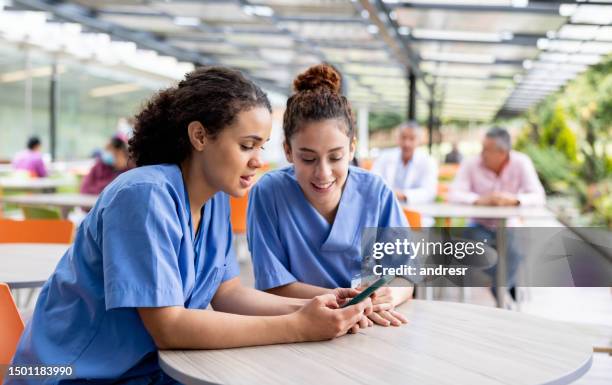 krankenschwestern machen eine pause und schauen sich in der cafeteria die sozialen medien an - krankenpflegepersonal stock-fotos und bilder