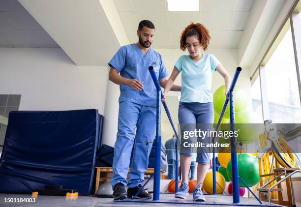 woman recovering from an injury and walking on bars - afkickcentrum stockfoto's en -beelden