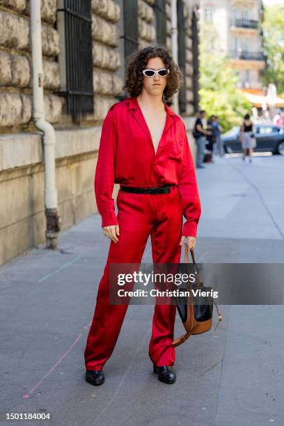Pim Spoor wears red silk button shirt, pants, bucket bag outside Loewe during the Menswear Spring/Summer 2024 as part of Paris Fashion Week on June...