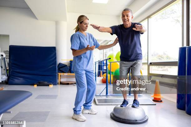 man doing physical therapy exercises using a balance ball - ortopedia imagens e fotografias de stock