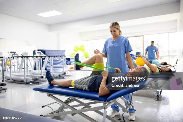 man doing physical therapy exercises using a stretch band - latina legs stockfoto's en -beelden